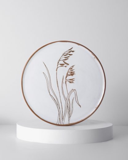 A Wildflower plate showing handcarved botanics on a handthrown plate, by Gallery Nordeinde